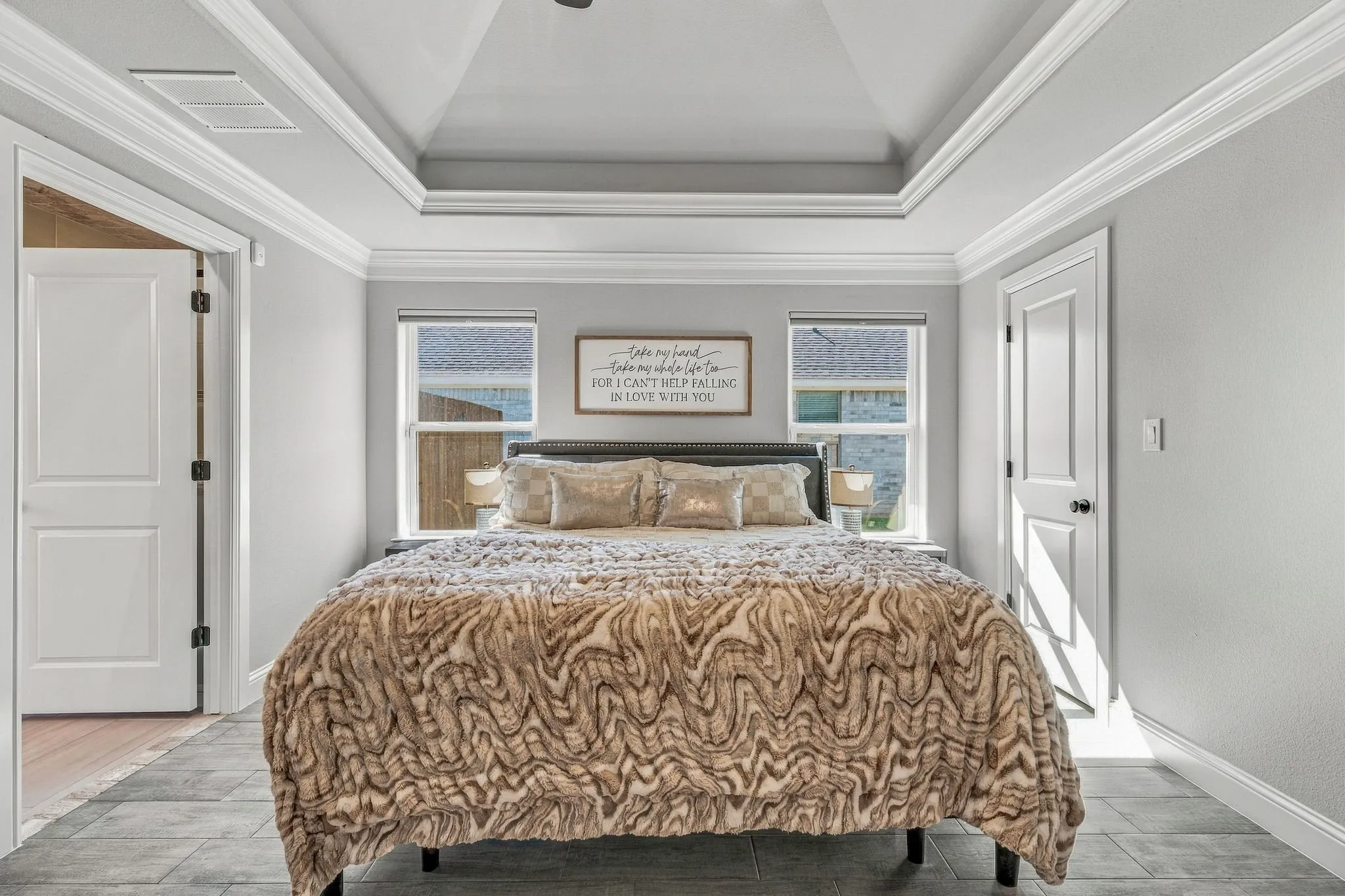 Tray ceiling with crown molding, two windows with blinds, light-toned walls, and tile flooring