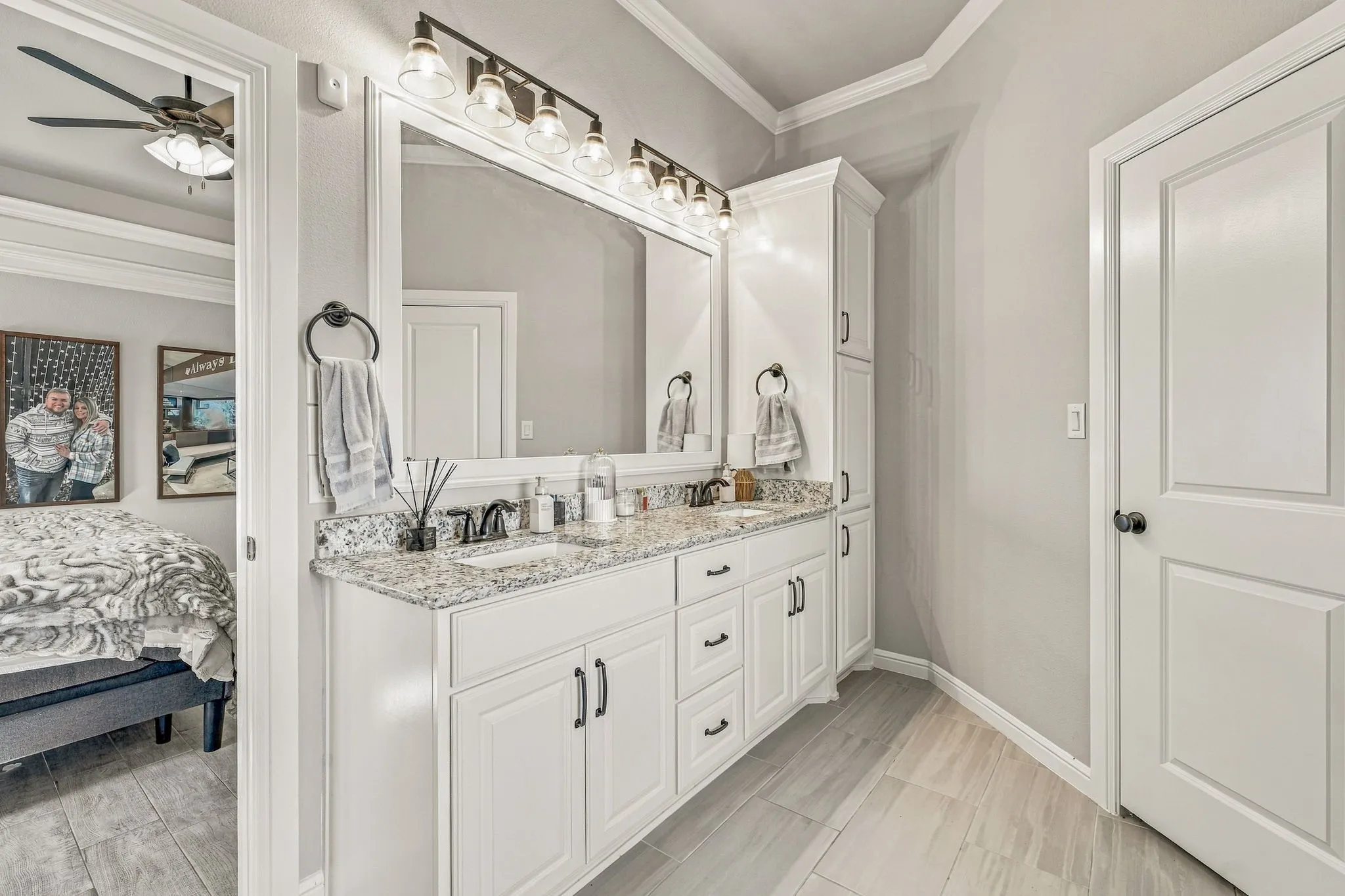 Dual vanity with granite countertop and undermount sinks, flanked by white cabinetry and a built-in tall linen cabinet