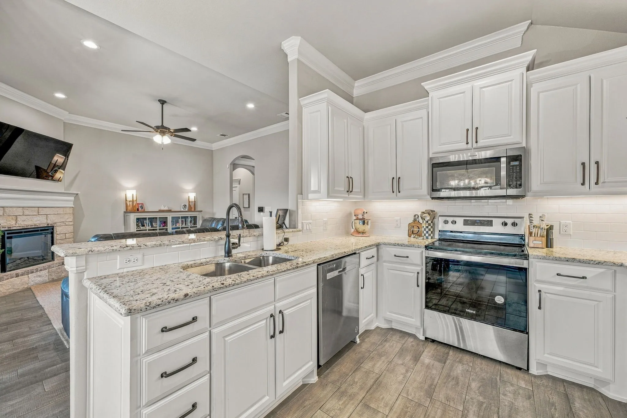 Kitchen featuring white cabinetry, granite countertops, stainless steel appliances, and wood-finish flooring
