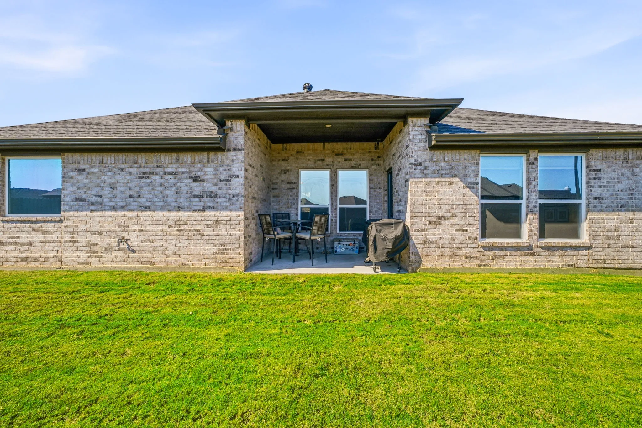 Brick exterior with a covered patio and multiple windows