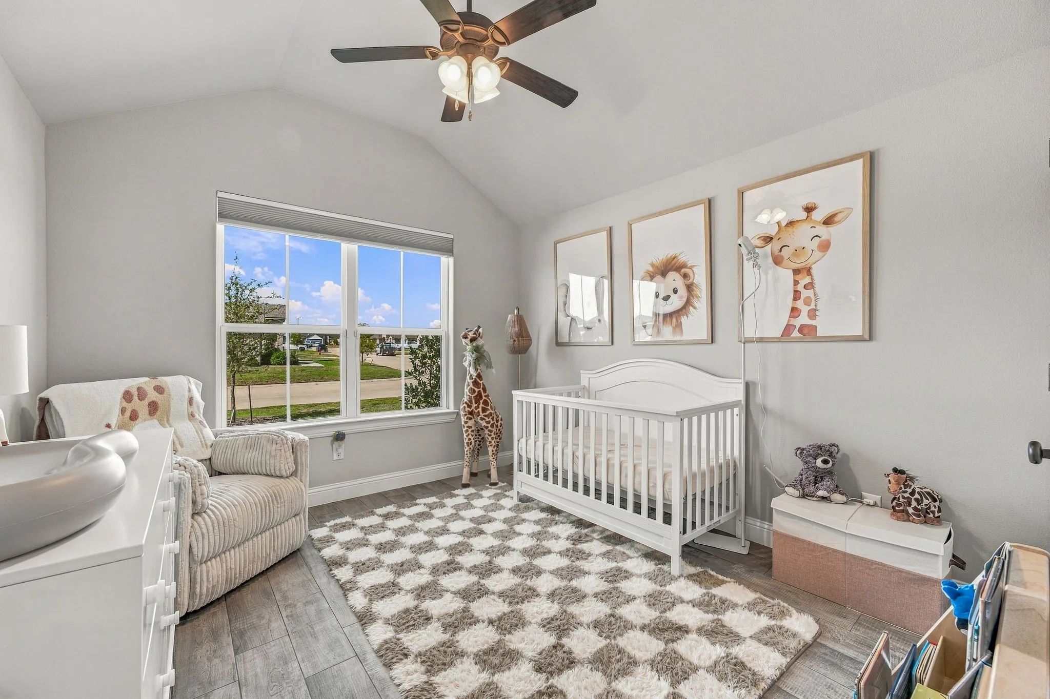Vaulted ceiling featuring a ceiling fan, wood-finish flooring, and a large window