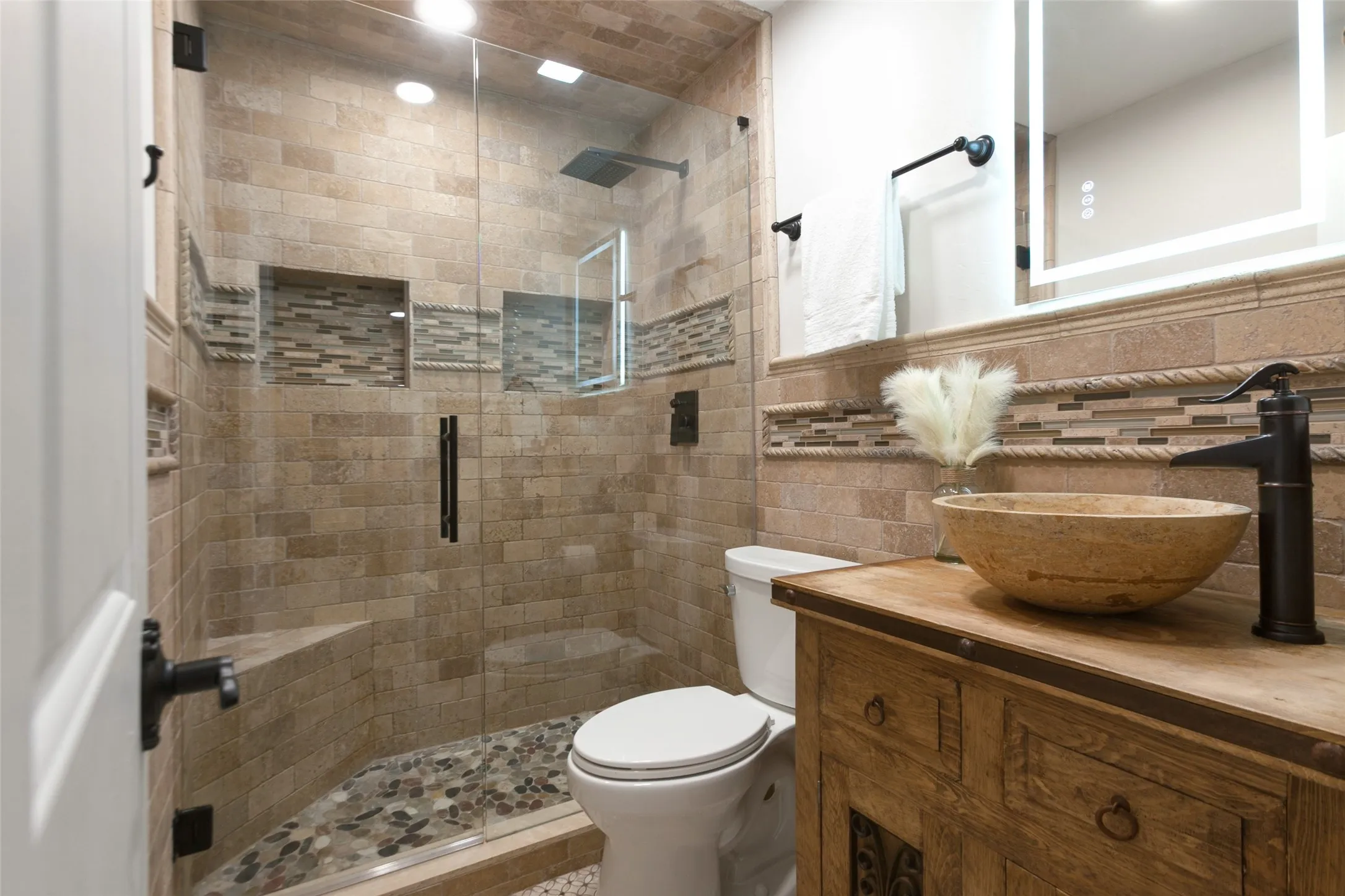 351 Vally Park Dr. - First-floor bathroom featuring a beautifully updated walk-in shower with glass enclosure, decorative mosaic tile accents, pebble tile shower floor, rustic wood vanity with vessel sink, and stylish fixtures.