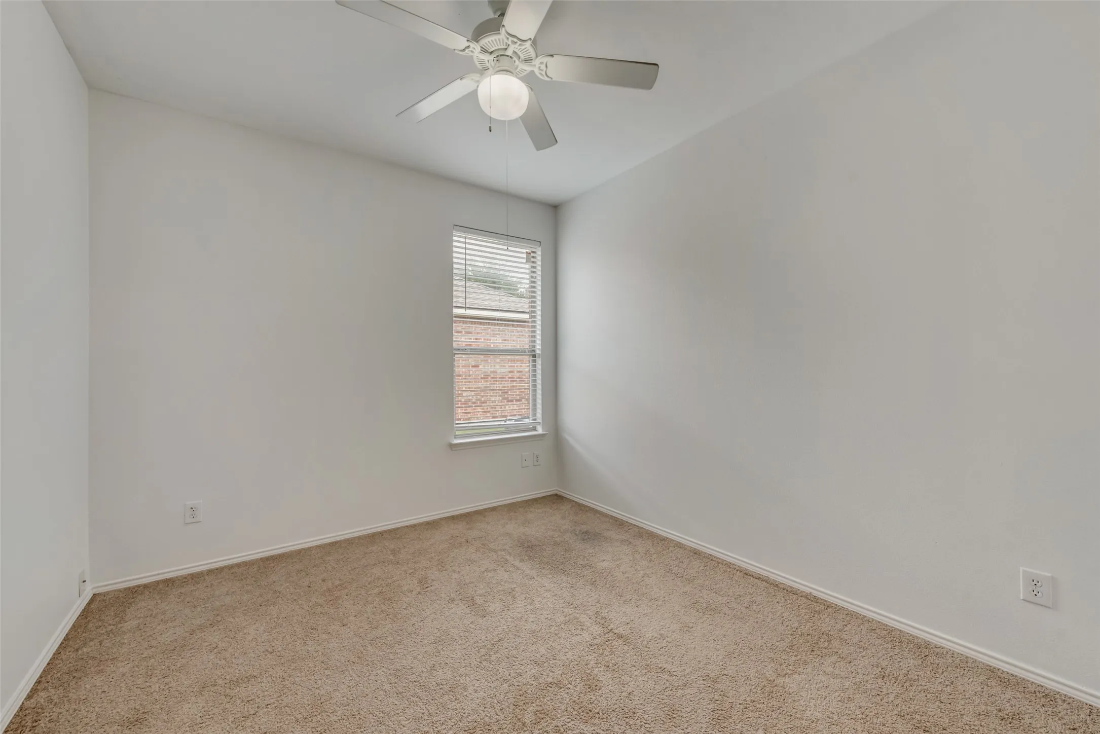 Neutral wall paint, ceiling fan with integrated lighting, window with blinds, and carpeted flooring