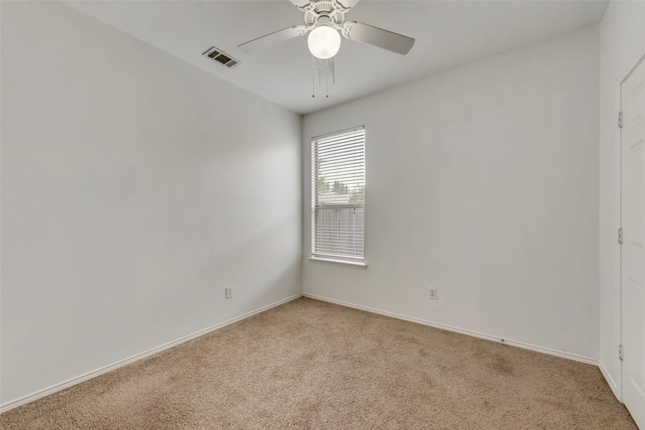 Carpeted room featuring a ceiling fan with integrated lighting, a window with blinds, and white walls