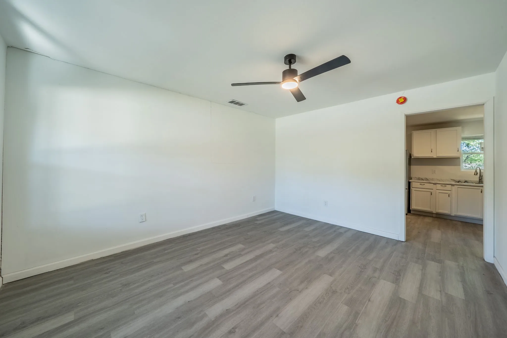 Wood-finish plank flooring, ceiling fan with integrated lighting, and white painted walls