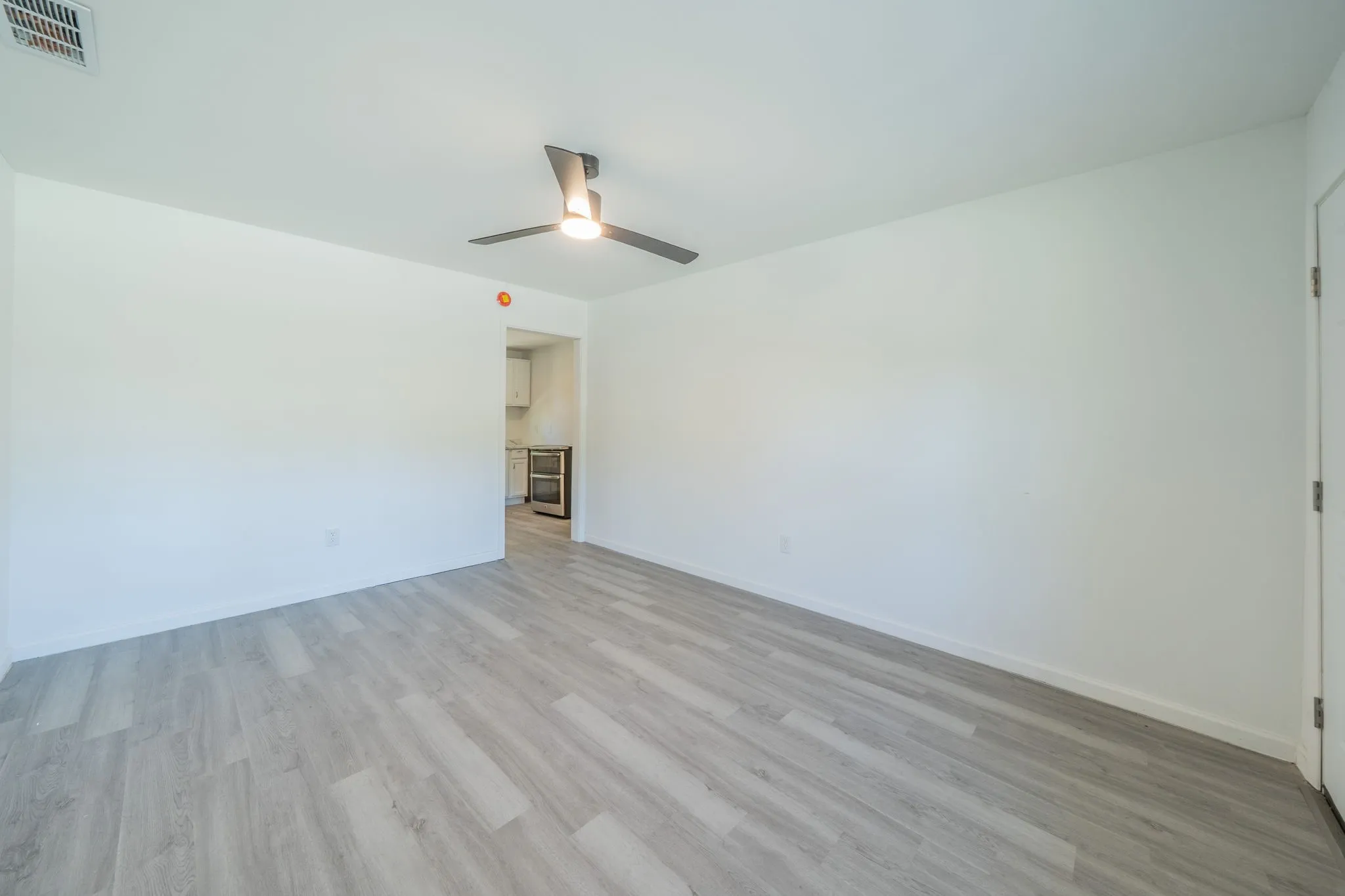 Light wood-finish flooring with a modern ceiling fan and recessed lighting
