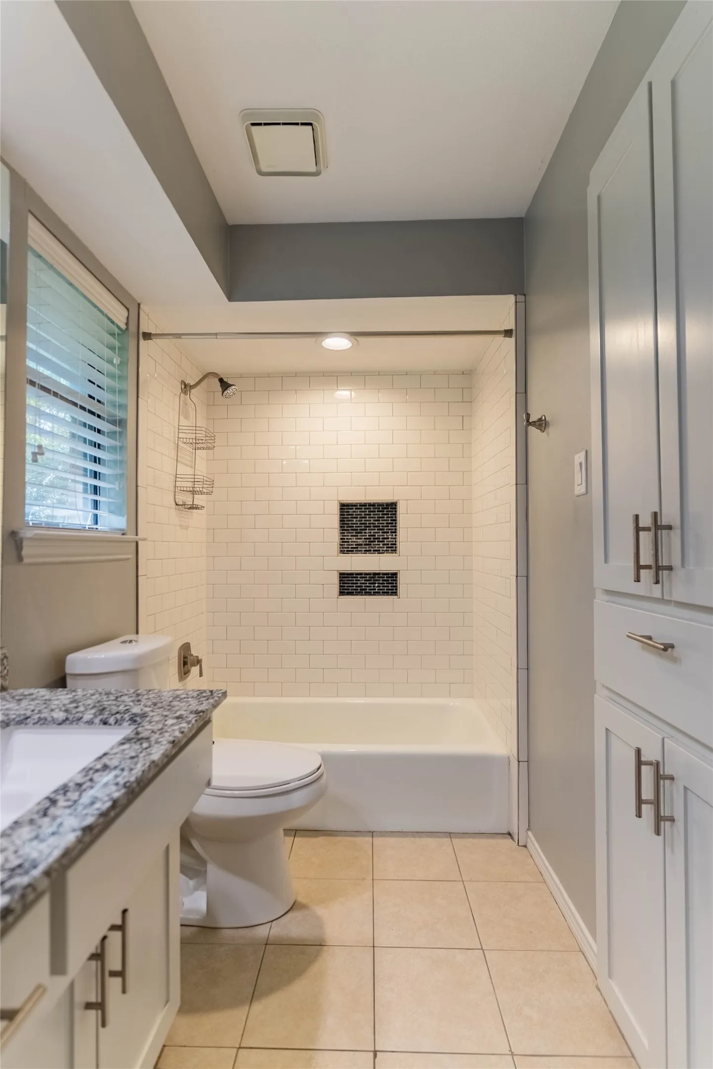 Bathroom with a white subway tile shower surround, integrated bathtub, and dual shower niches
