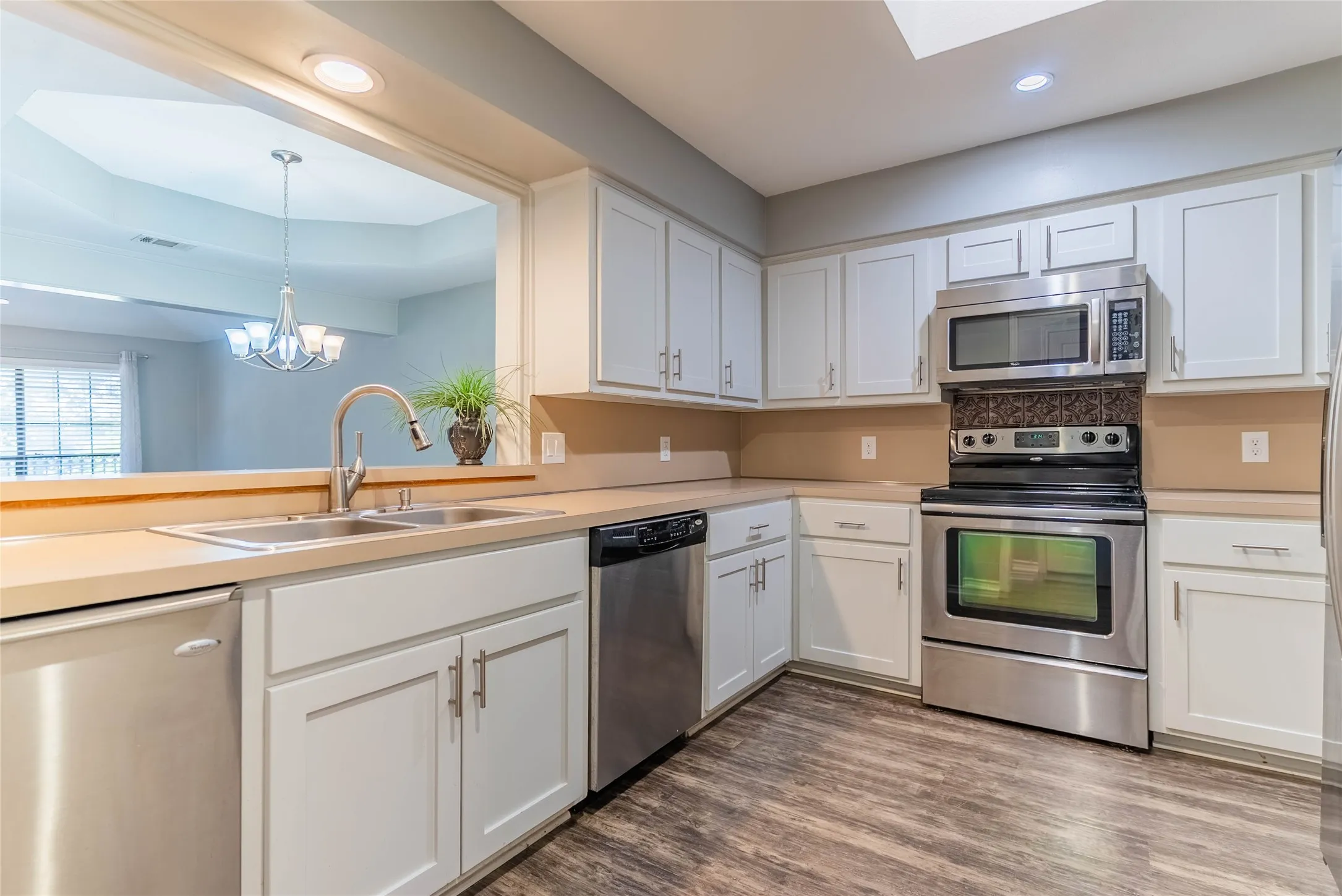 Kitchen featuring white cabinetry, light-toned countertops, wood-finish flooring, and stainless steel appliances