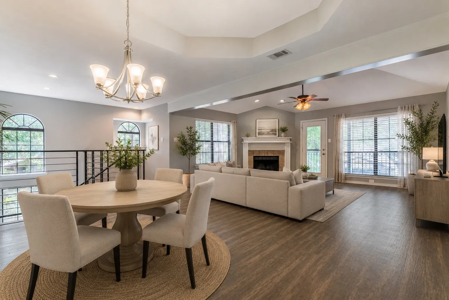 Expansive living area featuring vaulted ceilings, wood-finish flooring, a fireplace with a mantel, and multiple large windows
