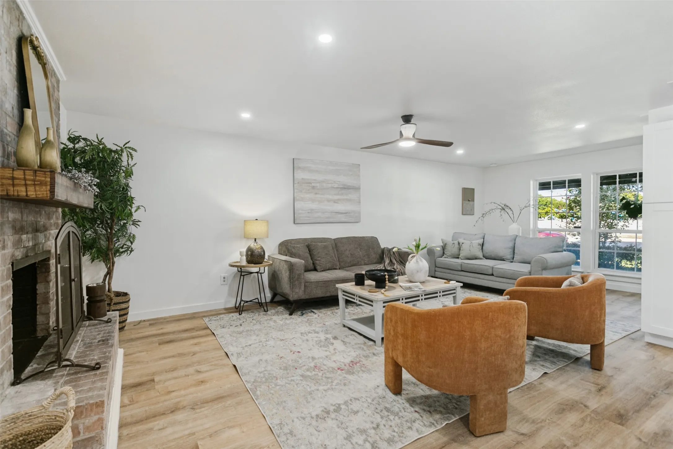 Living room featuring wood-finish flooring, a brick fireplace with a metal screen, recessed lighting, and a ceiling fan