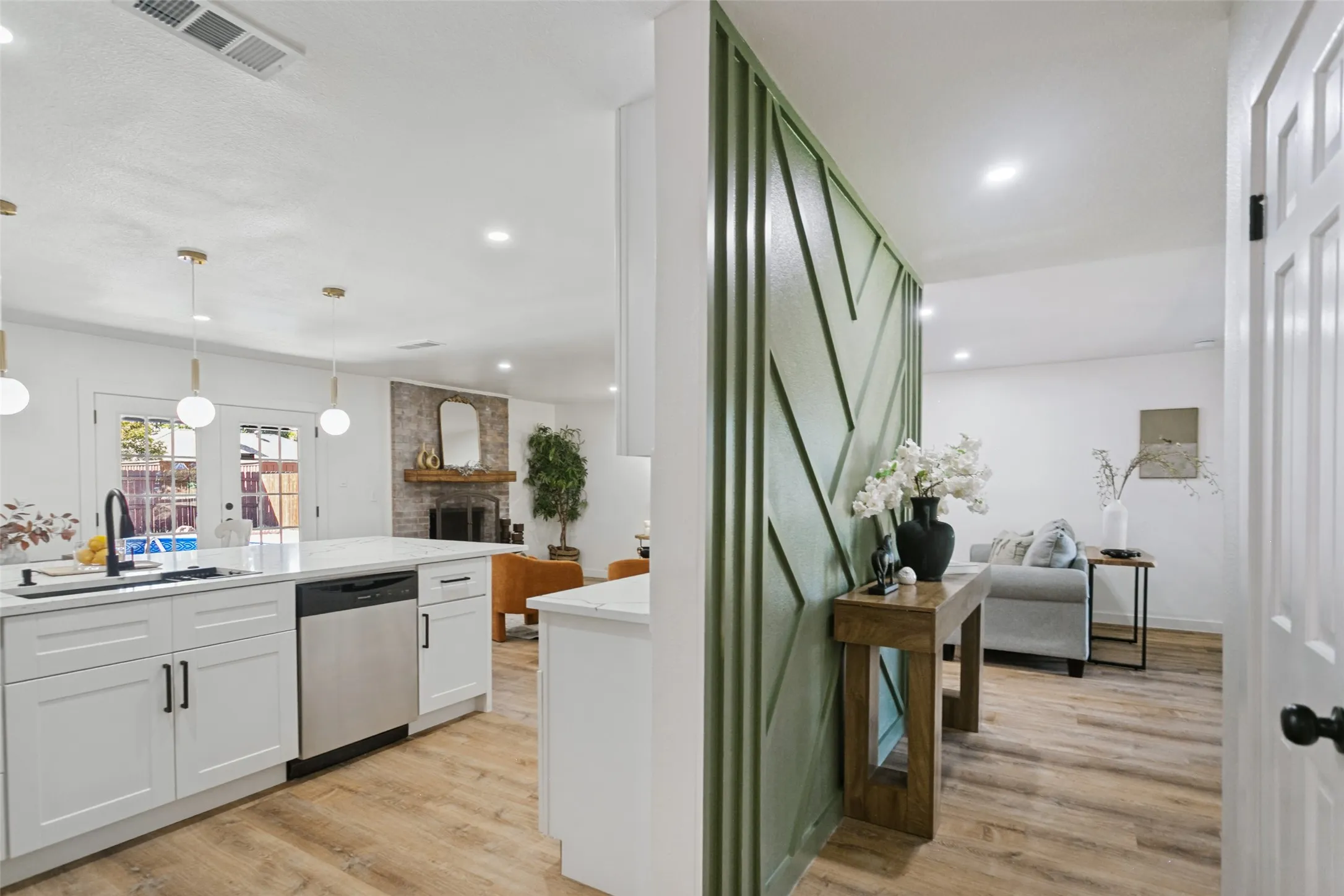 Kitchen featuring white cabinetry, a large island with a sink, stainless steel appliances, and wood-finish flooring