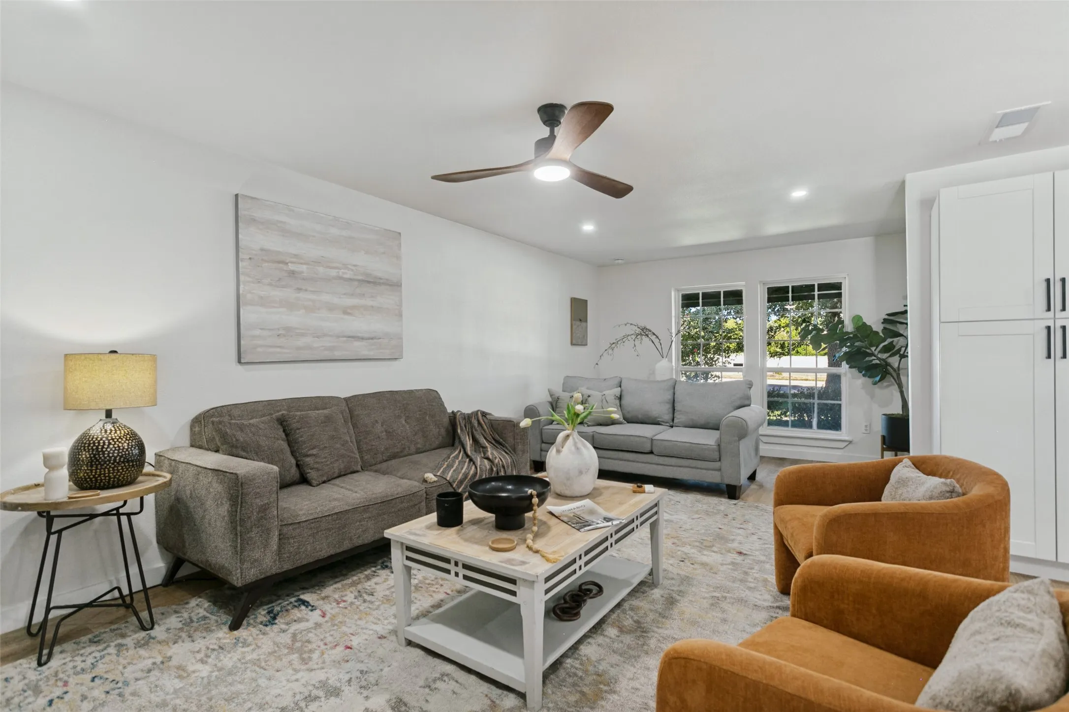Recessed lighting, ceiling fan, multiple windows, built-in cabinetry with dark hardware, and wood-finish flooring