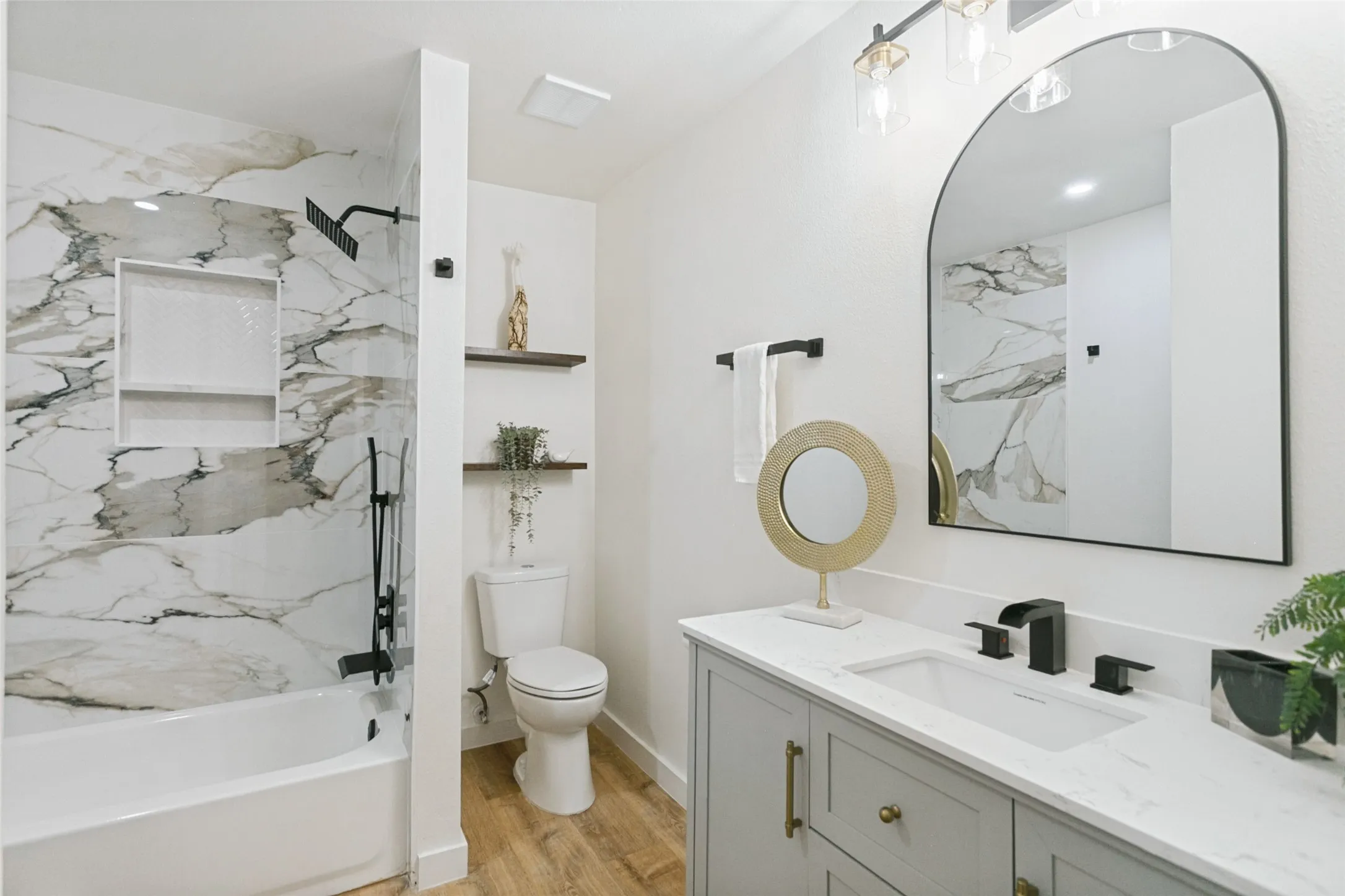 Bathtub with marble-look tile surround and recessed shelving