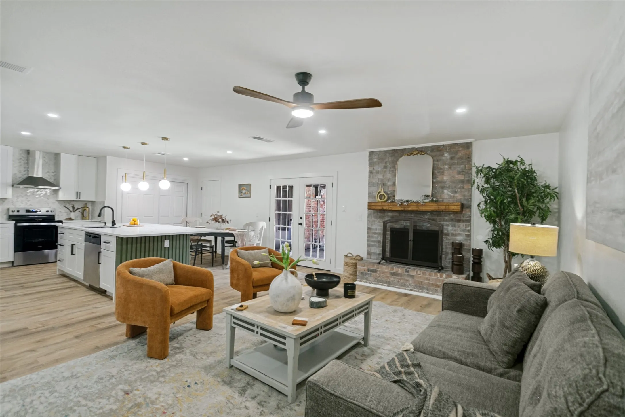 Open-concept living space featuring a brick fireplace with a wood mantel, a ceiling fan, and recessed lighting