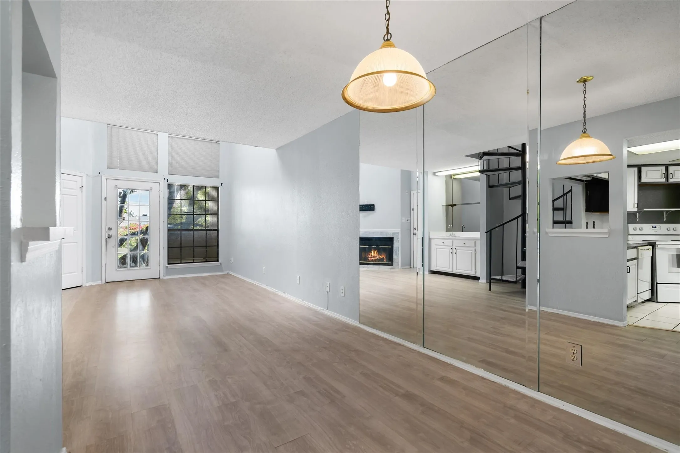 Wood-finish flooring throughout, full-length mirrored wall, built-in fireplace, and a spiral staircase