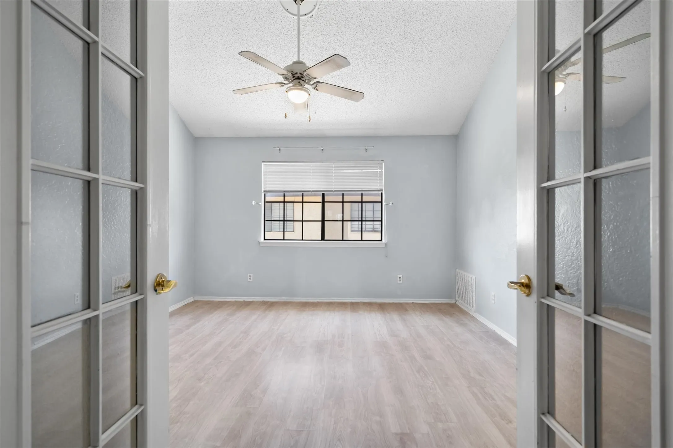 French doors with brass hardware, wood-finish flooring, ceiling fan with integrated lighting, and a window with blinds