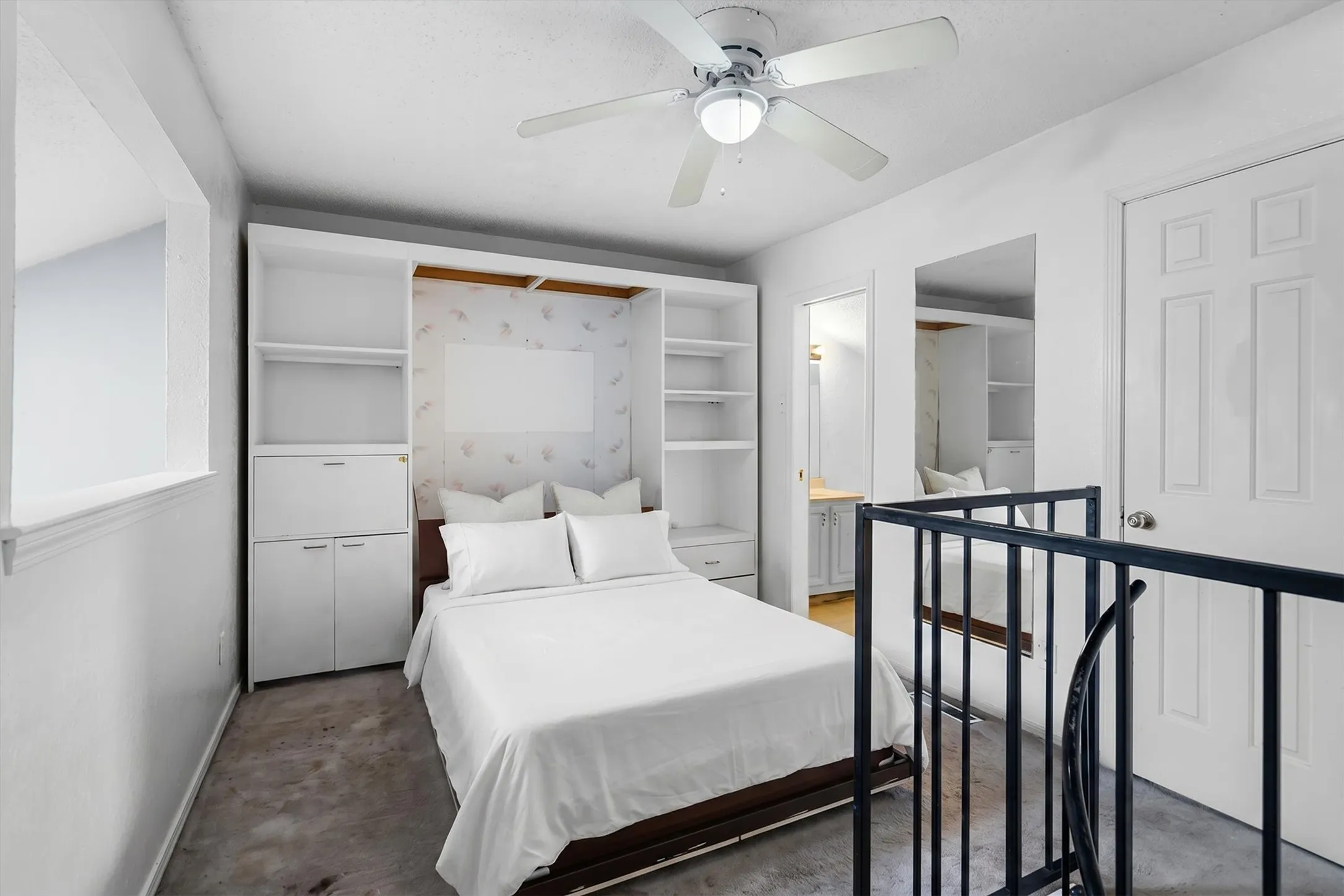 Built-in shelving with integrated storage, white panel door, and ceiling fan