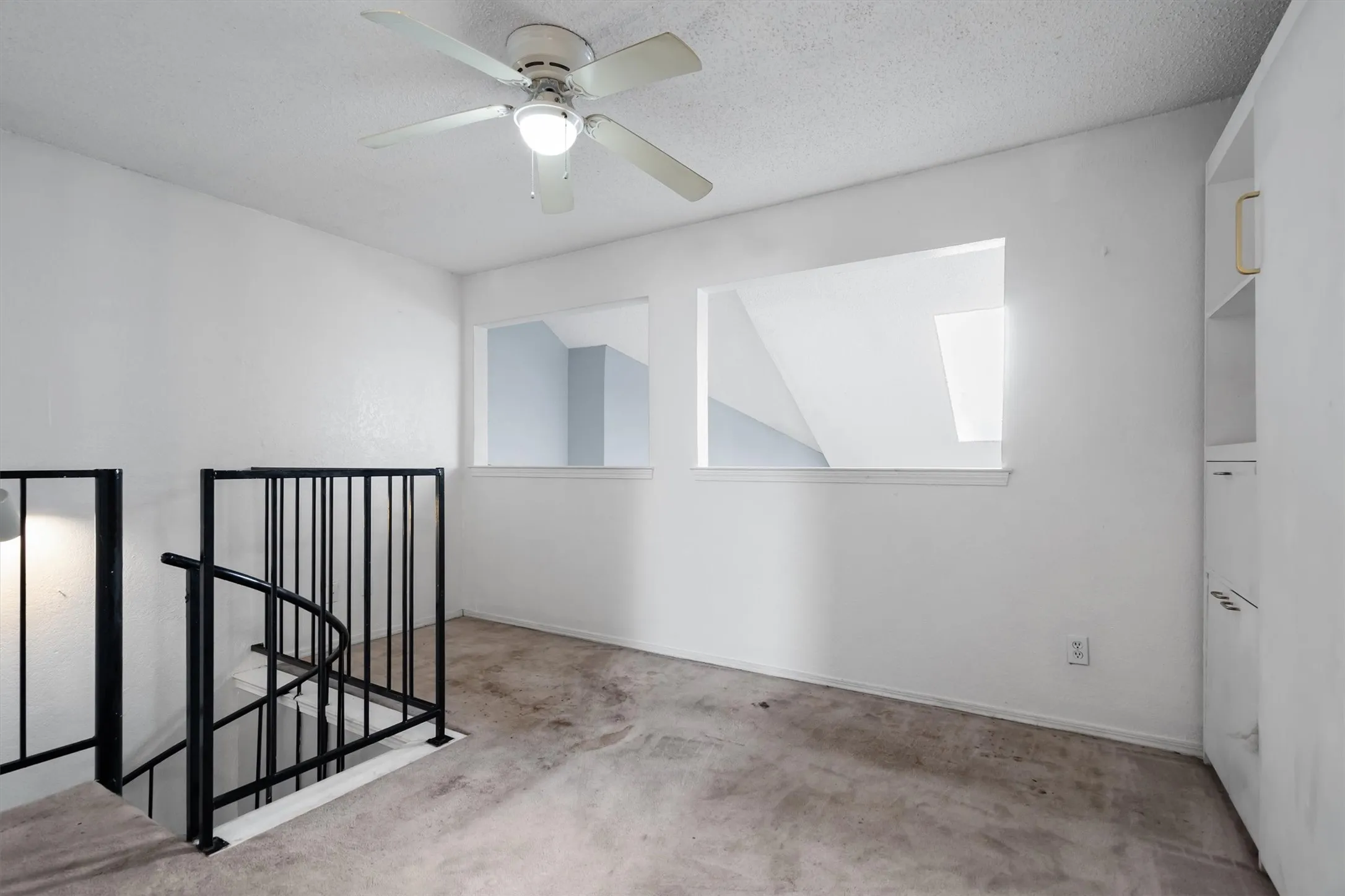 Ceiling fan with integrated lighting, built-in shelving, cutout wall features, and a spiral staircase with metal railing