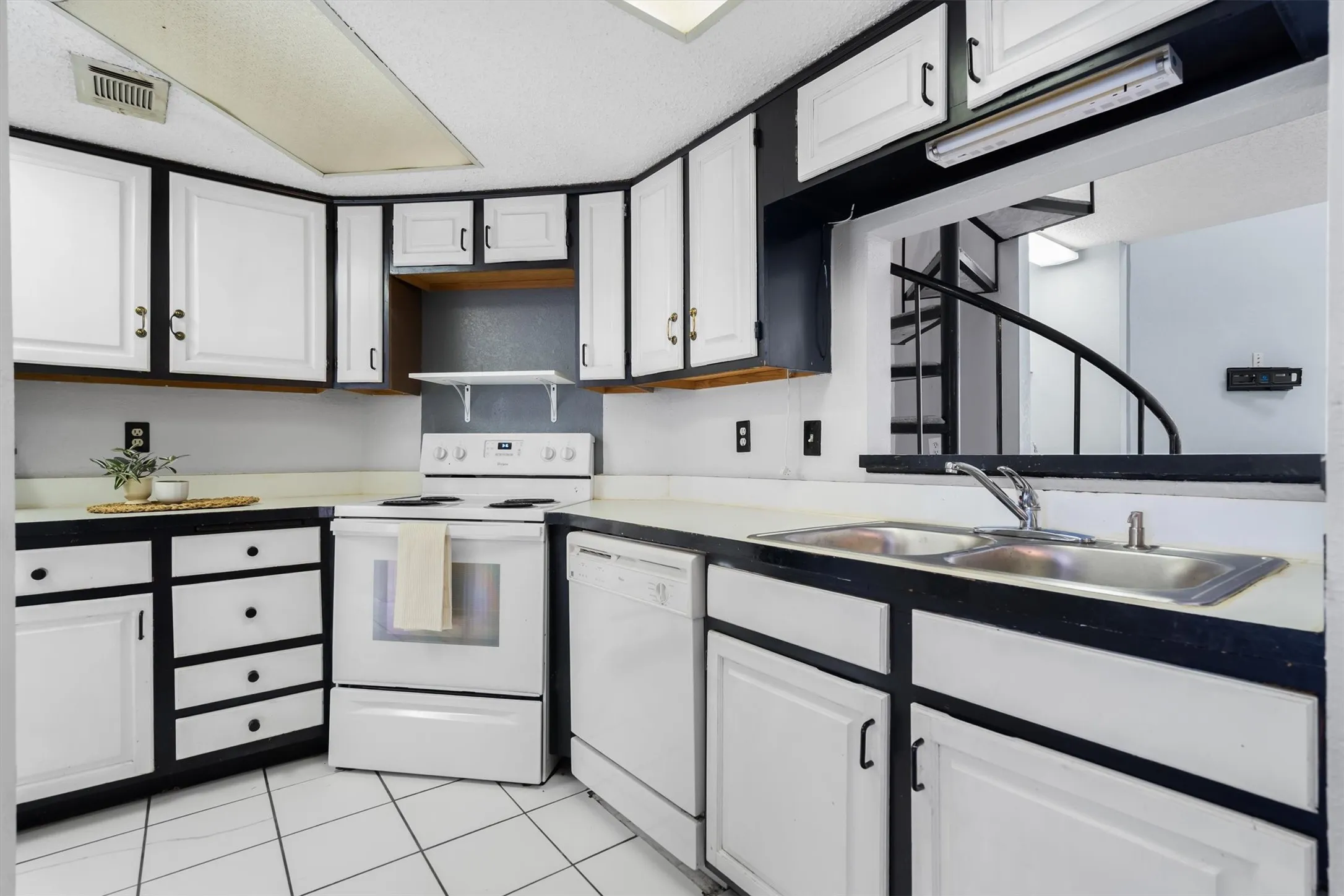 Kitchen featuring white cabinetry with black trim, white appliances, a double basin sink, and tile flooring