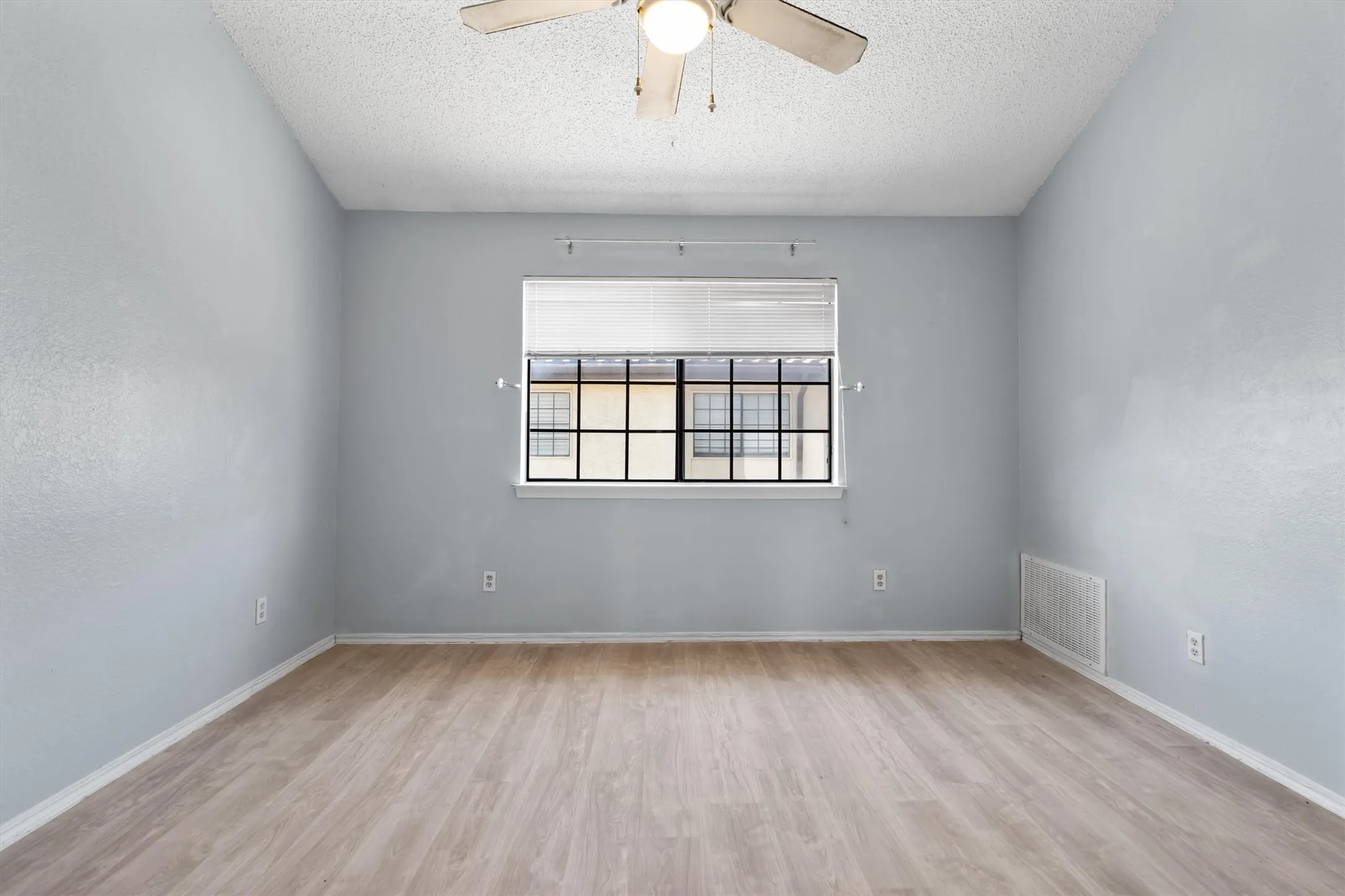 Light wood-finish flooring, ceiling fan, and a window with blinds