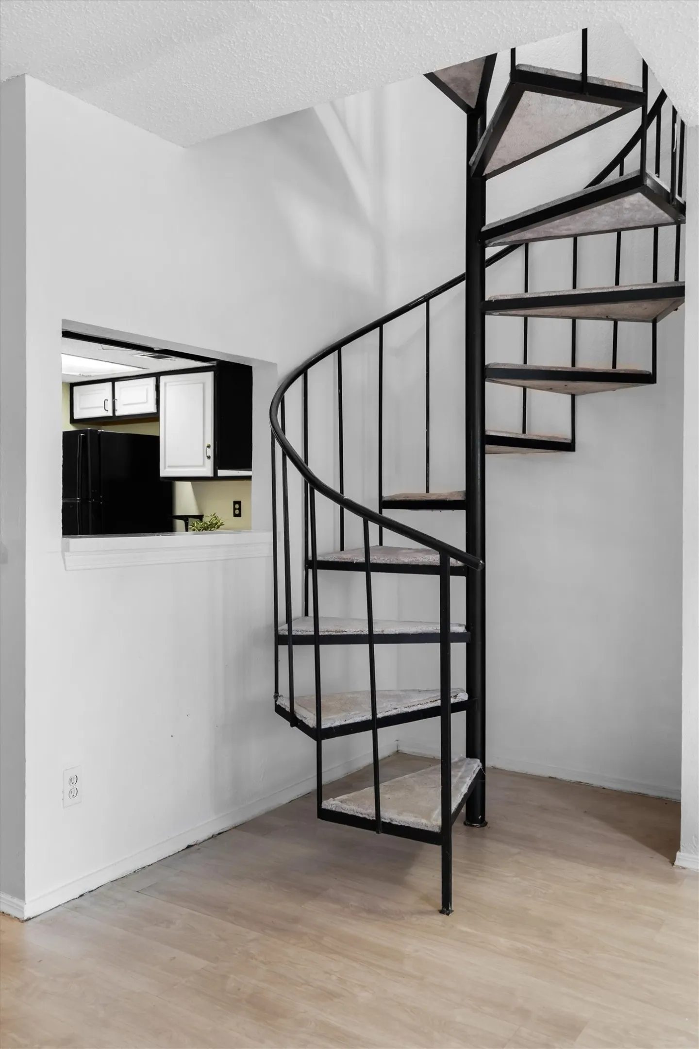 Black metal spiral staircase with carpeted treads