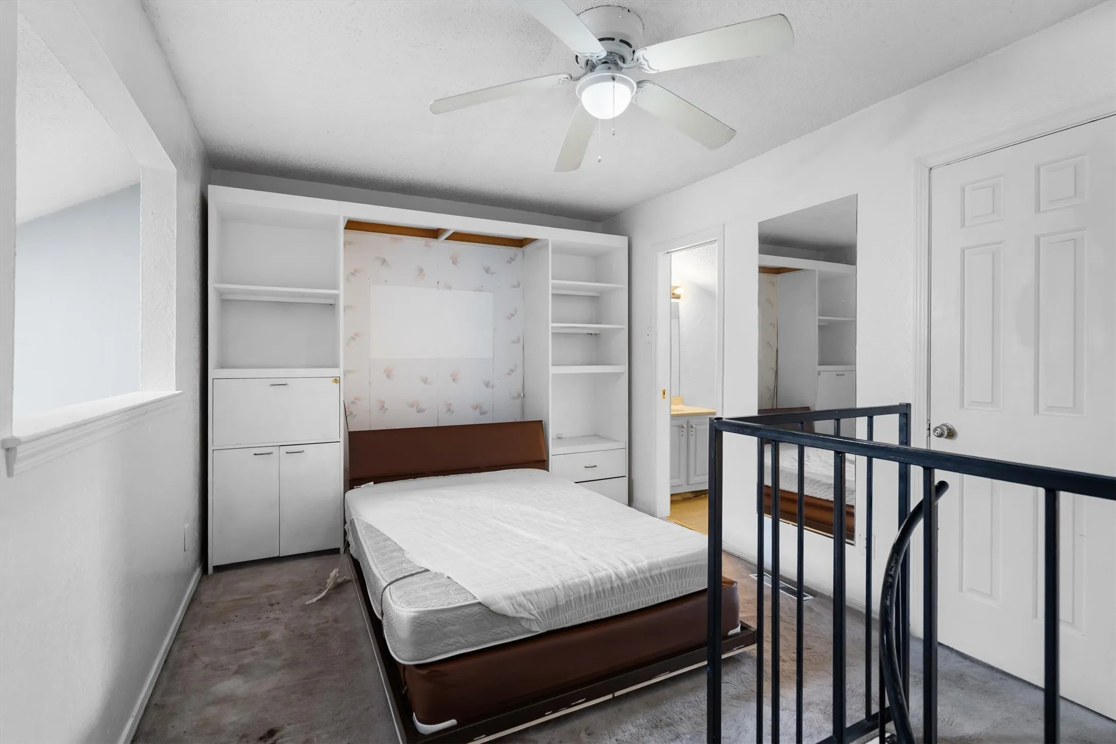 Built-in shelving and cabinetry, ceiling fan with integrated lighting, interior door with paneling, and a metal railing