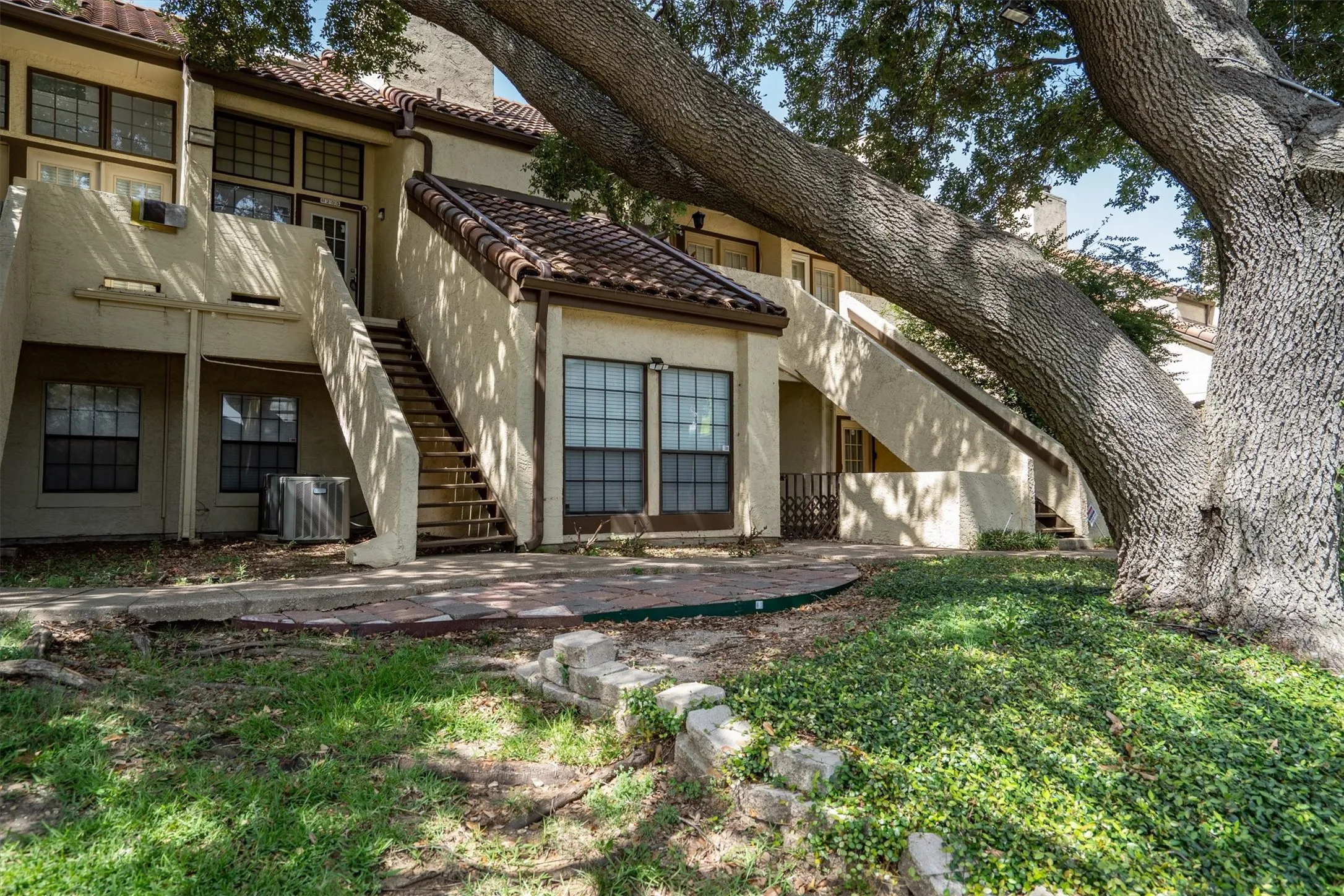 Mediterranean-style architecture featuring a tile roof, stucco exterior, multiple entryways, and exterior staircases