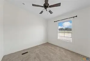 Carpeted flooring, white painted walls, a ceiling fan, and a window with horizontal blinds