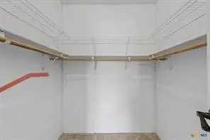 Walk-in closet featuring wire shelving, multiple wooden hanging rods, and light-colored walls