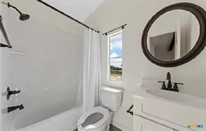 White vanity with integrated sink, black-finish faucet, and coordinating oval mirror