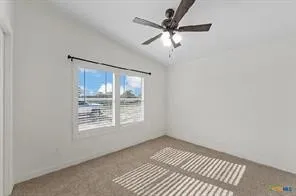 Vaulted ceiling featuring a ceiling fan with integrated lighting, wall-to-wall carpeting, and a double window with blinds