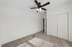 Neutral wall color, carpet flooring, ceiling fan with light fixture, and bifold closet doors