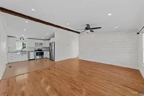 Hardwood flooring, exposed ceiling beam, recessed lighting, white shiplap accent wall, and stainless steel kitchen appliances