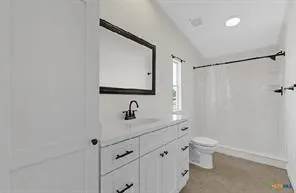 White vanity with black hardware, white countertop, rectangular sink, and black faucet