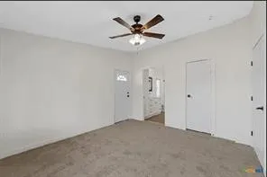 Carpeted flooring, white walls, and a ceiling fan with integrated lighting