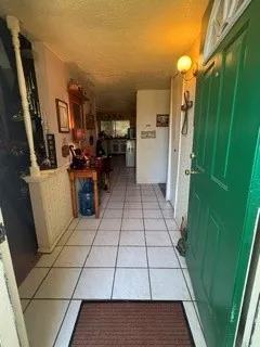 Tiled entryway with a solid panel door and a wall-mounted light fixture