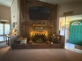 Brick fireplace with an extended hearth, vaulted ceiling, and a paneled front door with an arched transom window