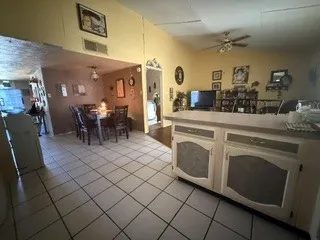 Tile flooring throughout, kitchen island with counter seating, ceiling fan, recessed lighting, and an arched doorway
