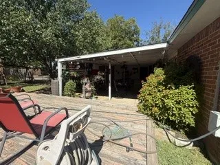 Expansive wood deck with a covered patio area, mature trees, and brick exterior