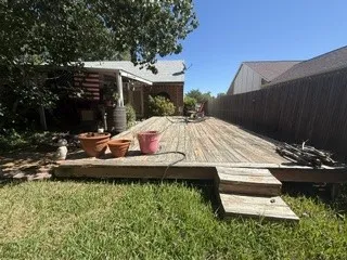 Expansive wooden deck with a built-in step, bordered by a privacy fence and a manicured lawn