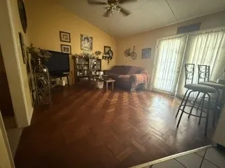 Vaulted ceiling with a ceiling fan, wood-finish flooring with a herringbone pattern, and a sliding glass door