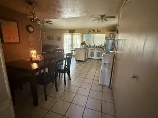 White tile flooring throughout, with a ceiling fan in the kitchen area