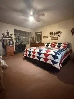 Carpeted bedroom with a ceiling fan, sconce lighting, and a window to an adjoining room