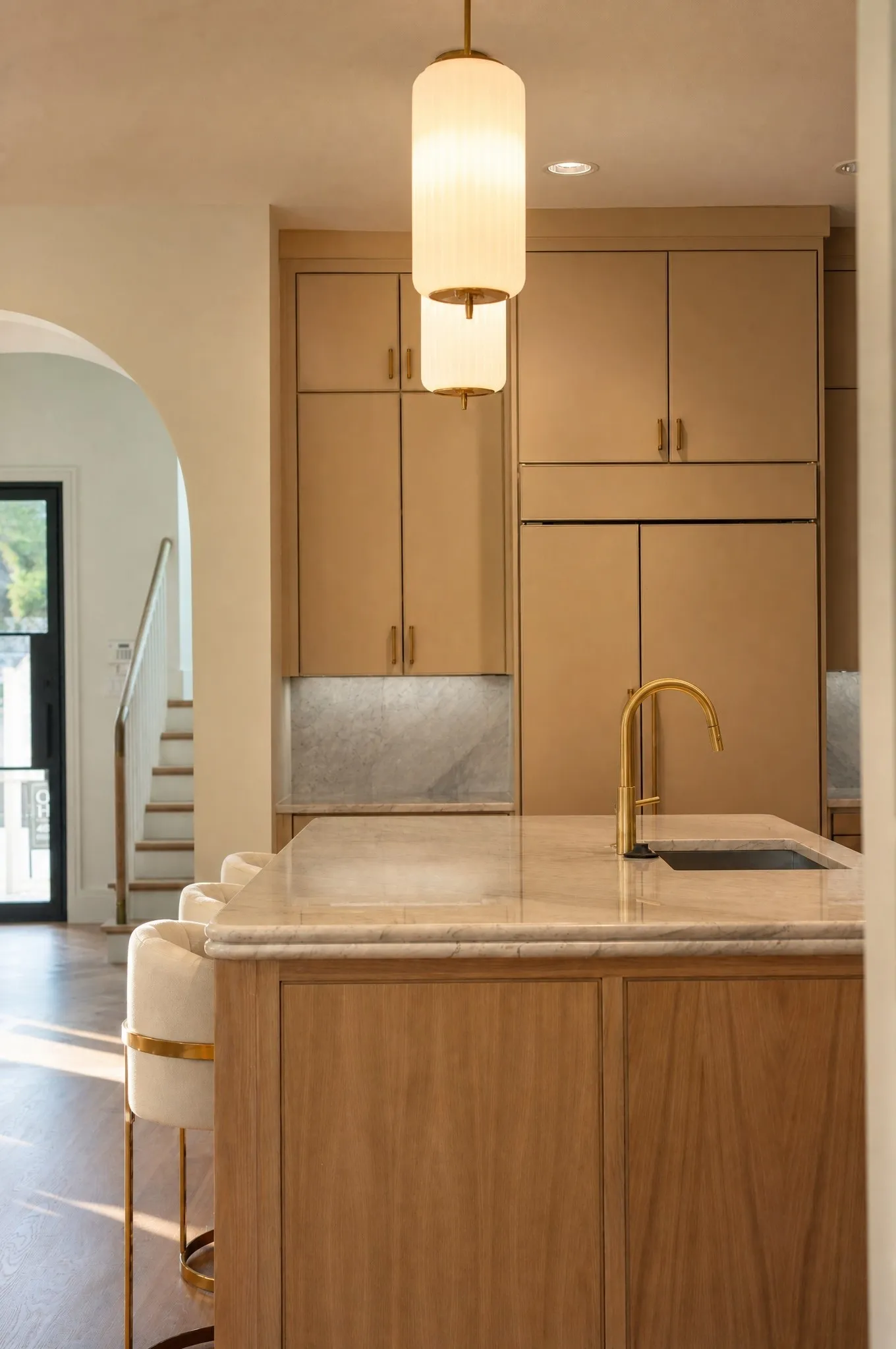 Kitchen island with natural wood-finish cabinetry, a stone countertop, and a gooseneck faucet
