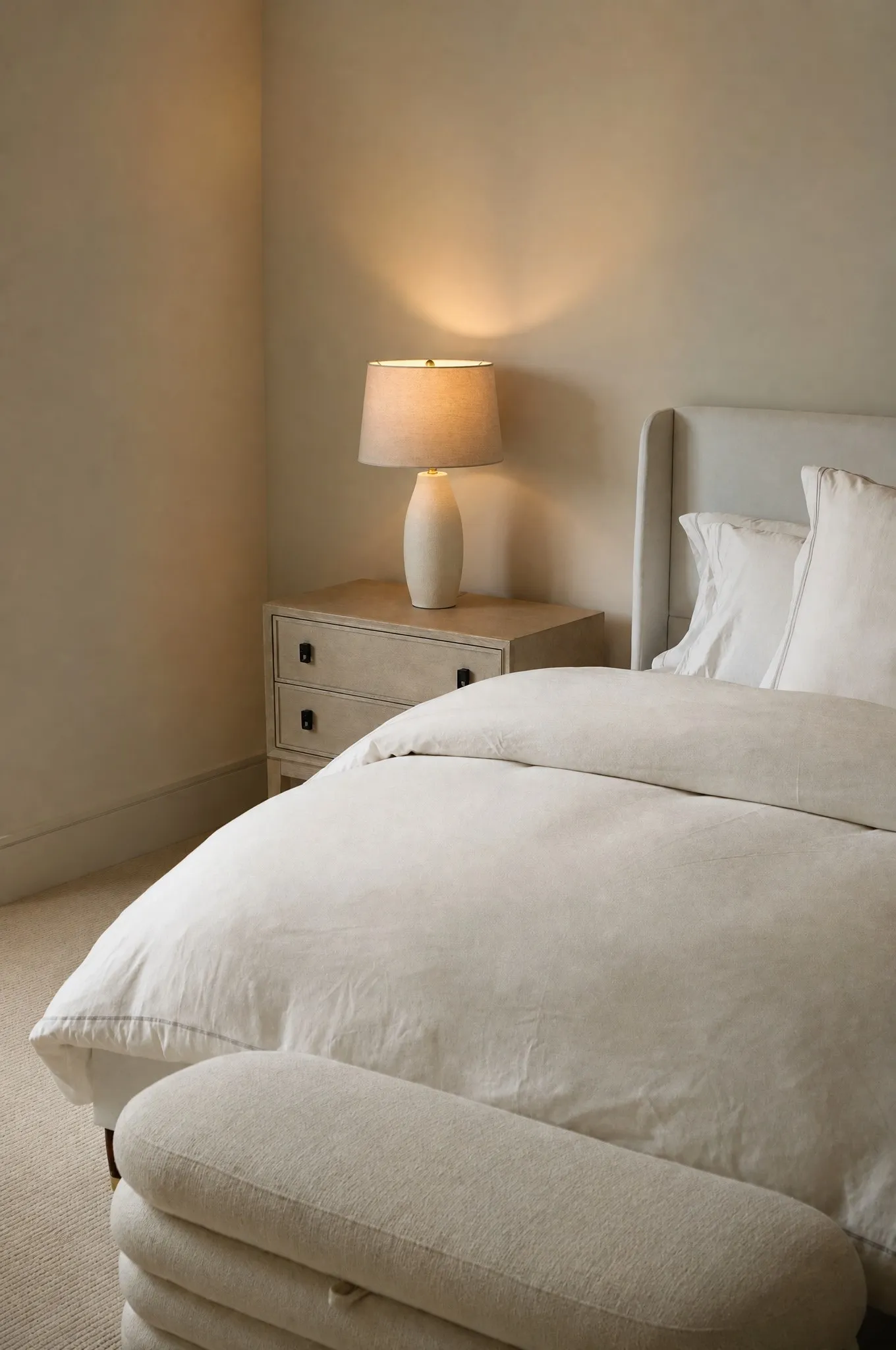 Upholstered winged headboard with a light wood-finish nightstand featuring dark hardware