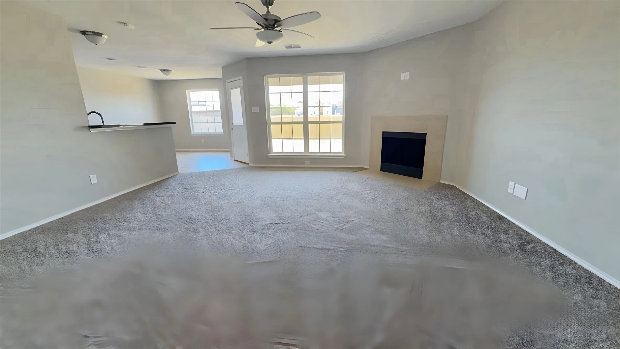 Carpeted living area featuring a built-in fireplace, ceiling fan, and multiple windows