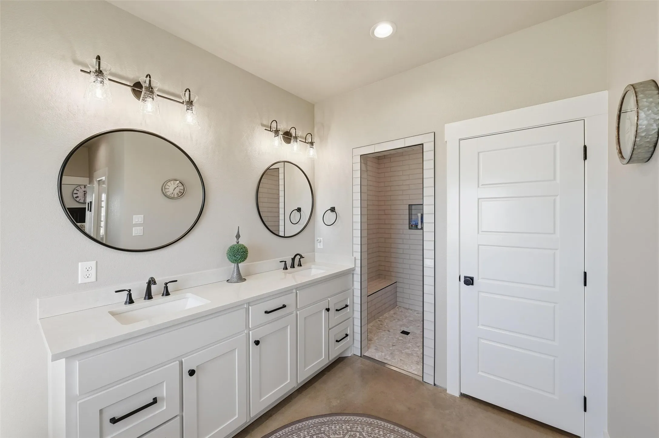 Primary Bathroom with double vanity, a walk in shower, recessed lighting, and finished concrete floors
