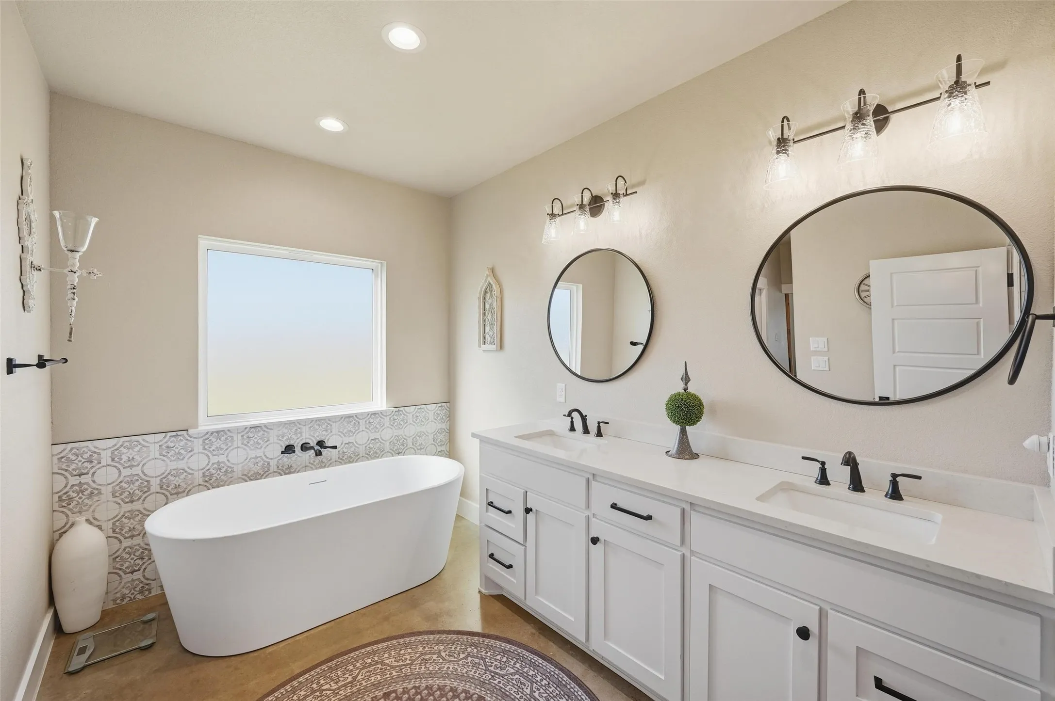 Primary Bathroom with a freestanding bath, double vanity, recessed lighting, and tile walls