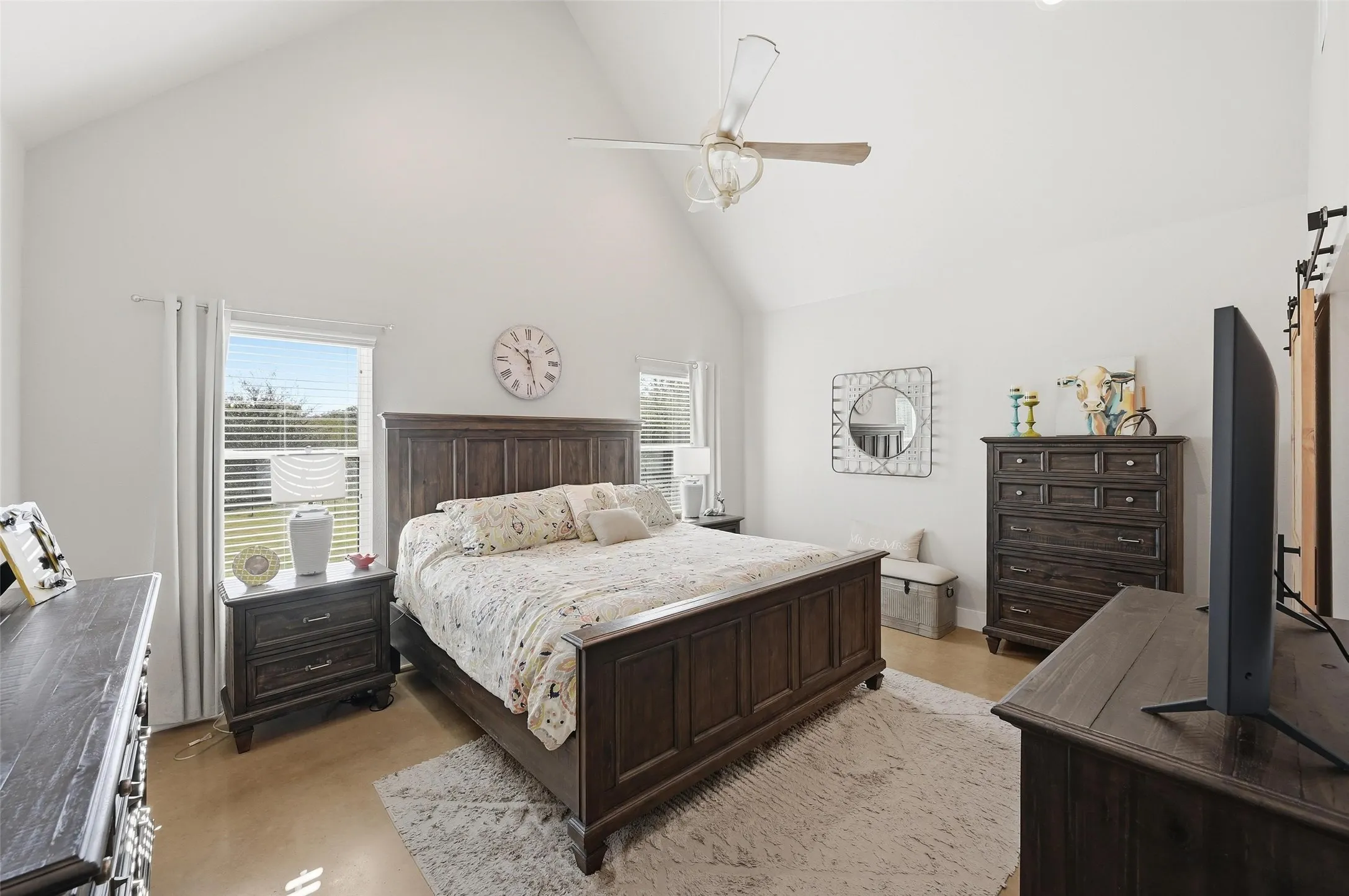 Bedroom featuring high vaulted ceiling, ceiling fan, and a barn door