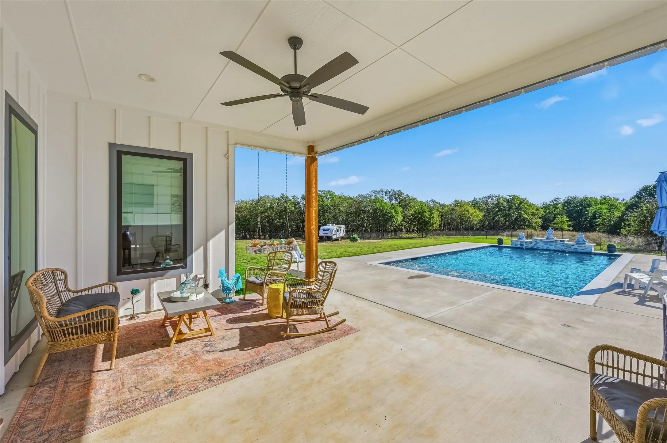 Swimming pool featuring a ceiling fan, a patio, and view of wooded area